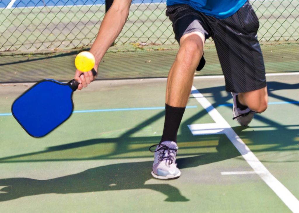 A young man holding a pickleball paddle with the continental grip