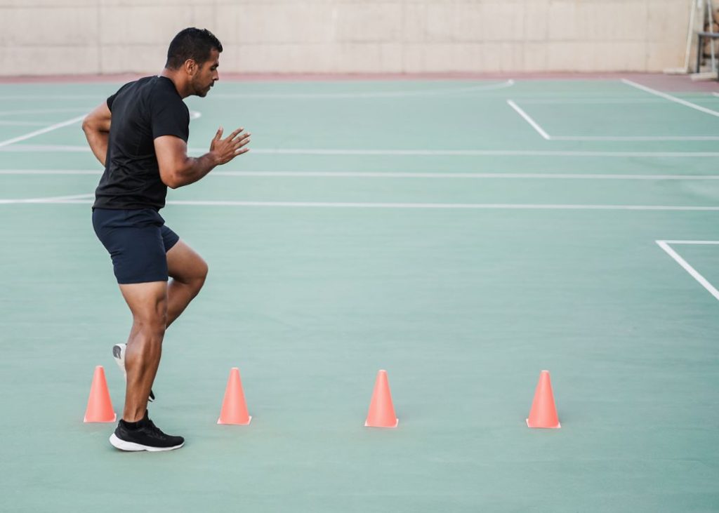 A man doing footwork exercises with four cones